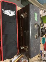 Closed Stanley metal toolbox with a black handle and latches, alongside a black and red Jobmate tool bag.