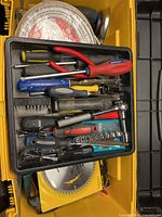 Photo of the removable toolbox tray with various small hand tools including pliers, screwdrivers, ratchet wrench, wire cutters, and sockets