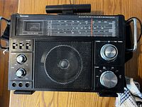 Front view of a black rectangular Venturer multiband radio showing the speaker grille, tuning and band knobs, control knobs, and two-way meter.