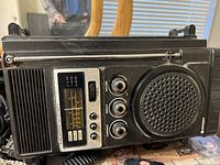 Front view of vintage Hitachi transistor TV showing speaker, tuning dial, control knobs, and speaker grille