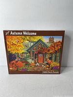 Front of the puzzle box showing vibrant fall house scene with detailed autumn foliage and seasonal decorations, text indicating 1000 pieces.