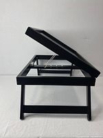 Side view of the black breakfast tray showing folded legs and partially open tilting top surface.