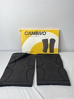 Two black Cambivo knee support sleeves laid flat, showing front pattern and branding, next to yellow and white Cambivo box with illustrative knee support images.