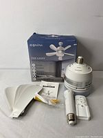 Photo showing the Conini fan light motor unit, four white fan blades, LED bulb, remote control, user manual, and packaging box.