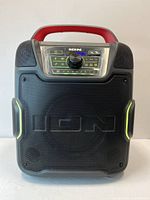Front view of the Ion Pathfinder 320 portable Bluetooth speaker showing the control panel, speaker grille, red handle, and detailing.