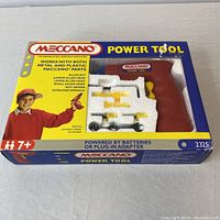 View of the front of the Meccano Power Tool toy package showing the tool and included accessories in blister pack, with branding and age recommendation on box.
