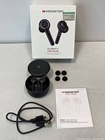 Box of Monster Clarity 102 Plus wireless earbuds and included accessories: charging case, extra ear tips, USB charging cable, and instruction manual.