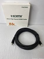 Photo of the HDMI cable with its original white box packaging labeled with brand 'CRATREE' and 'Ultra High Speed HDMI Cable 8k'. Cable is black with a smooth surface.
