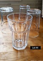 Photo showing four clear tall tumbler glasses on a wooden surface with a textured geometric vertical facets design.