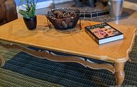 Wooden rectangular coffee table with some objects on top showing top surface condition and design details.
