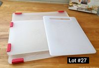 Photo showing the three plastic cutting boards stacked and spread on a wooden surface, highlighting their size difference and red rubber grips on two boards.