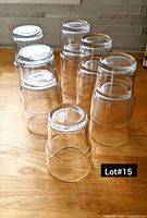 Photo showing eleven clear tall drinking glasses placed upside down on a wooden surface.