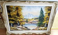 Front view of a large framed painting depicting a landscape with lake, mountain, and trees in autumn colors.
