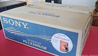 Photo of the original Sony PS-LX300USB stereo turntable system packaging box on a table, displaying the brand and model, and mention of included LP to CD transfer software.