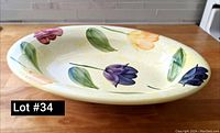Side view showing the oval shape and multiple colored tulips painted around the rim on cream background.