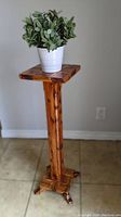 Full view of the wooden plant stand showing the square top, central column, and cross base with four short feet.