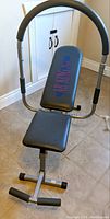 View of the Ab King Pro workout bench showing the padded curved handles, seat, and backrest with logo.