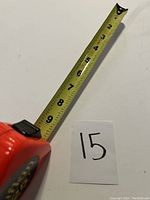 Side view of red Lufkin tape measure with tape extended showing measurement markings.