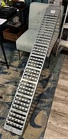 Full view of aluminum motorcycle ramp leaning on chair