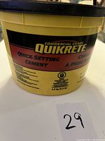 Yellow Quikrete commercial grade quick-setting cement container with black lid, labeled 4.5 kg (10 lbs) quick-setting cement.