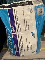 Photo of a blue and white bag labeled 'Self Leveling Compound' indicating grey color and usage instructions in multiple languages.