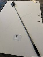 Full length telescopic inspection mirror showing the extended metallic shaft and black foam handle.