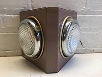 Front view of the triangular metal light fixture showing two mounted lights with textured glass and chrome trim.