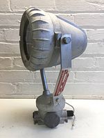 Front side of the metal industrial light showing round light head and mounting bracket.