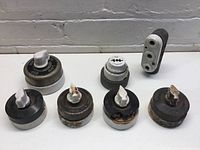 Seven ceramic electrical components, mainly rotary switches with white toggles and one ceramic outlet block.