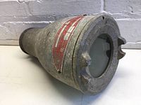 Side angle view of the metal explosion-proof housing showing the cylindrical shape and glass window end.