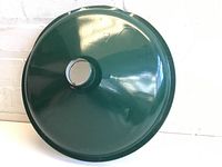 Green enamel light shade showing the exterior surface with a central mounting hole and minor chipping around the edge.
