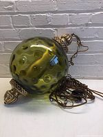 Full view of the green glass globe light with attached chain and metal end caps showing the overall item.