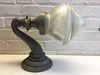 Full side view of the Holophane outdoor light showing glass globe and iron arm/base.