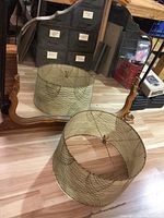 Photo showing large antique mirror with wooden frame and crowned decorative top, reflecting the surrounding area including the lamp shade and storage boxes.