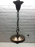 Full view of the pendant light fixture hanging from chain against wall