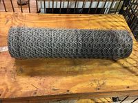 Top view of the rolled chicken wire placed on a wooden table showing the hexagonal wire mesh pattern.