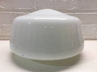 Side view of smooth opaque white milk glass globe with rounded top and wide open bottom.