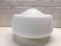 Side view of the opaque white milk glass schoolhouse globe light shade showing its rounded dome shape and smooth surface.