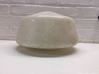 Side view of milk glass schoolhouse globe shade showing rounded shape and aging stains.