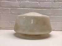 Side view of milk glass schoolhouse globe light shade showing shape and discoloration