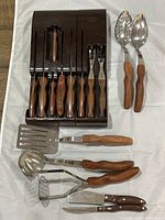 Wall-mounted case with wood-handled utensils inserted and additional utensils beside it