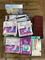 Lot components including bladder protection pads, heating pad, compression stockings, sound machine, and bathmat arranged on floor for listing.