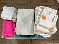 Photo showing the stacked towels and washcloths in various colors alongside folded sheets with animal print.
