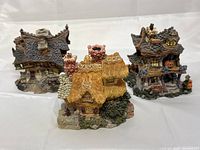 Three different Boyd's Bearly-Built Villages collectible miniature houses grouped for display, showing detailed roofs, chimneys, and textured elements.