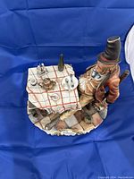 Side view of the full porcelain figurine showing the seated man, table with tea set, and base.