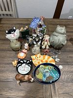 Overview of all cat-themed figurines, decorative dishes, and wall hangers arranged on table