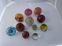 Top view of the 11 glass balls arranged in a semi-circle showing variety of colors, sizes and designs.