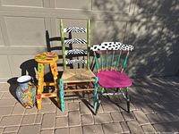 Full set photo showing two hand painted ladder back chairs, one fruit painted stool, and a southwest style ceramic vase on tiled ground.