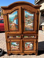 Front view of hand painted TV armoire showing colorful Southwest village scenes on upper and lower cabinet doors and drawer fronts