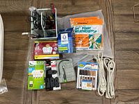 Overall view of hardware lot showing assorted pliers, power cords, weatherstripping, lightbulbs, screwdriver set, furniture markers, and Brita filter cartridges.